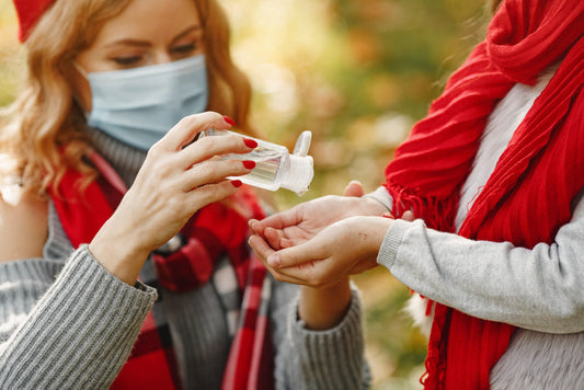 a lady wearing mask senetizing a girl for germs protection